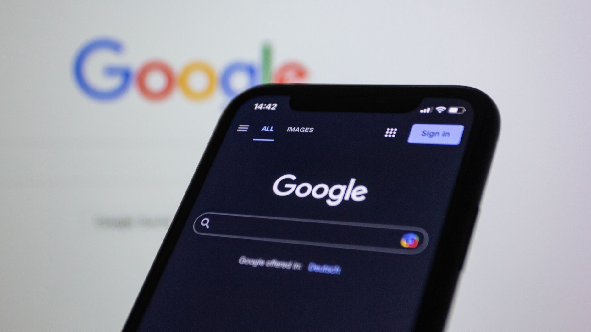 Smartphone con pantalla de búsqueda de Google y Discover en modo oscuro